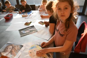 dziewczynka rysuje swoją wersję Dziewczyny z Perłą, w tle widać też pracę innych dzieci 