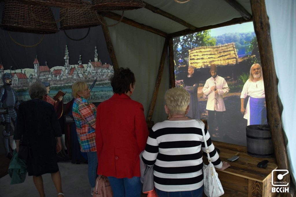 zwiedzający oglądają instalacje dotyczące zawodów w średniowieczu i pokazujące średniowieczny targ 