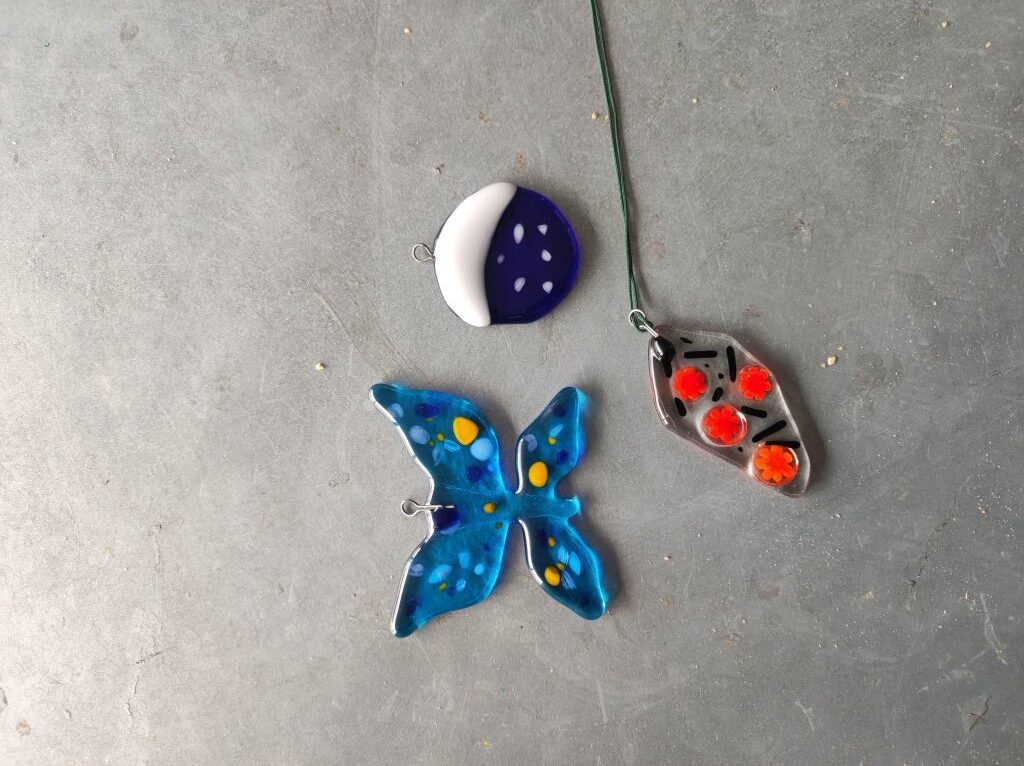 trzy zawieszki ze szkła wśród nich zawieszka w kształcie motyla 